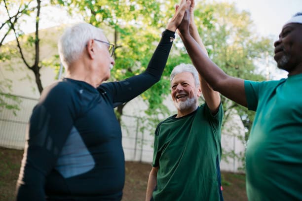 Happy small diverse group of elderly men hanging out together after a healthy recreational endeavour, giving a high five to each other like a team